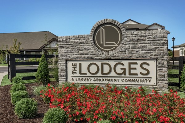 The Lodges: Elegant sign surrounded by lush landscaping at a luxury apartment community