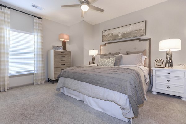 Cozy bedroom with plush bedding and large windows at The Lodges on English Station Rd Apartments, luxury living in a serene setting