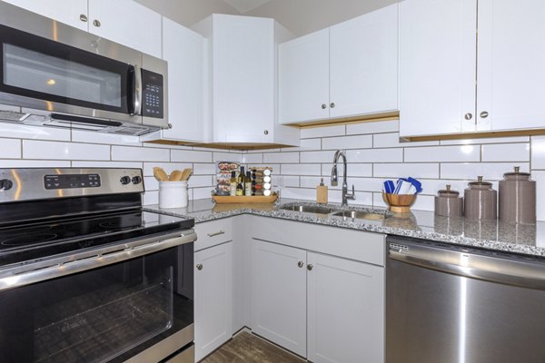 Modern kitchen with stainless steel appliances in The Lodges on English Station Rd Apartments