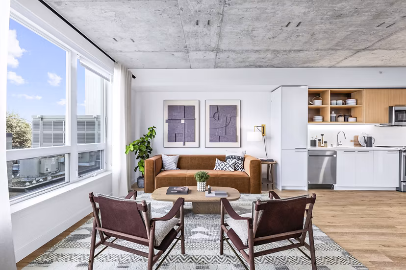 Living room with modern design elements at Connection on Broadway Apartments featuring comfy seating and stylish decor