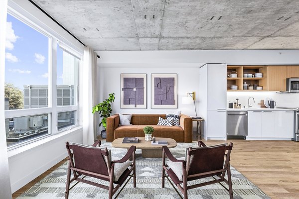 Living room with modern design elements at Connection on Broadway Apartments featuring comfy seating and stylish decor
