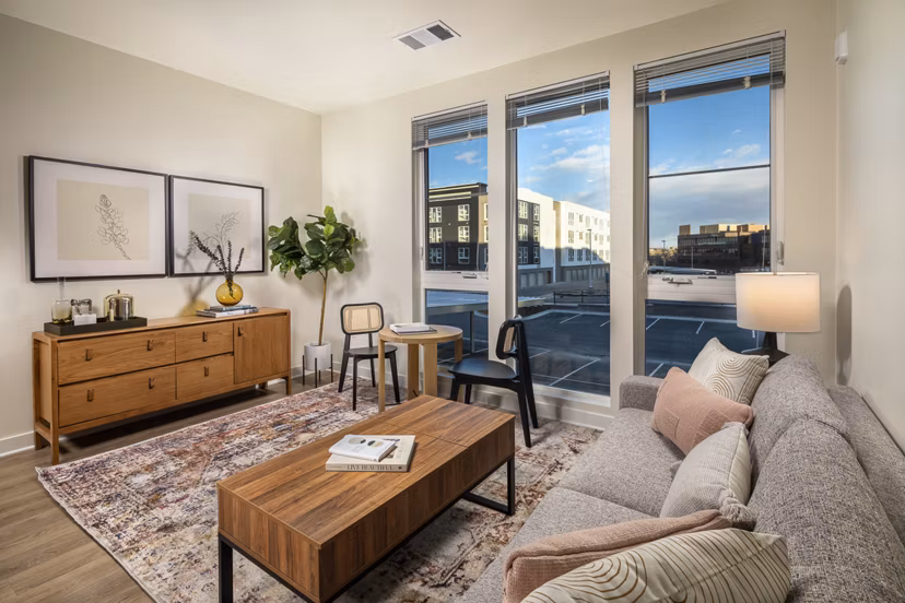Spacious living room with modern decor and large windows at Revel Apartments