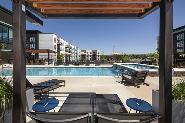 Luxury pool with lounge chairs and lush landscaping at Revel Apartments, ideal for relaxation and leisure