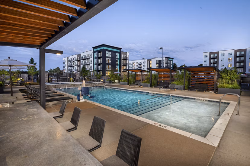 Revel Apartments: Luxurious pool area with modern lounge chairs in a vibrant community setting