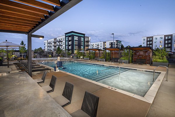 Revel Apartments: Luxurious pool area with modern lounge chairs in a vibrant community setting