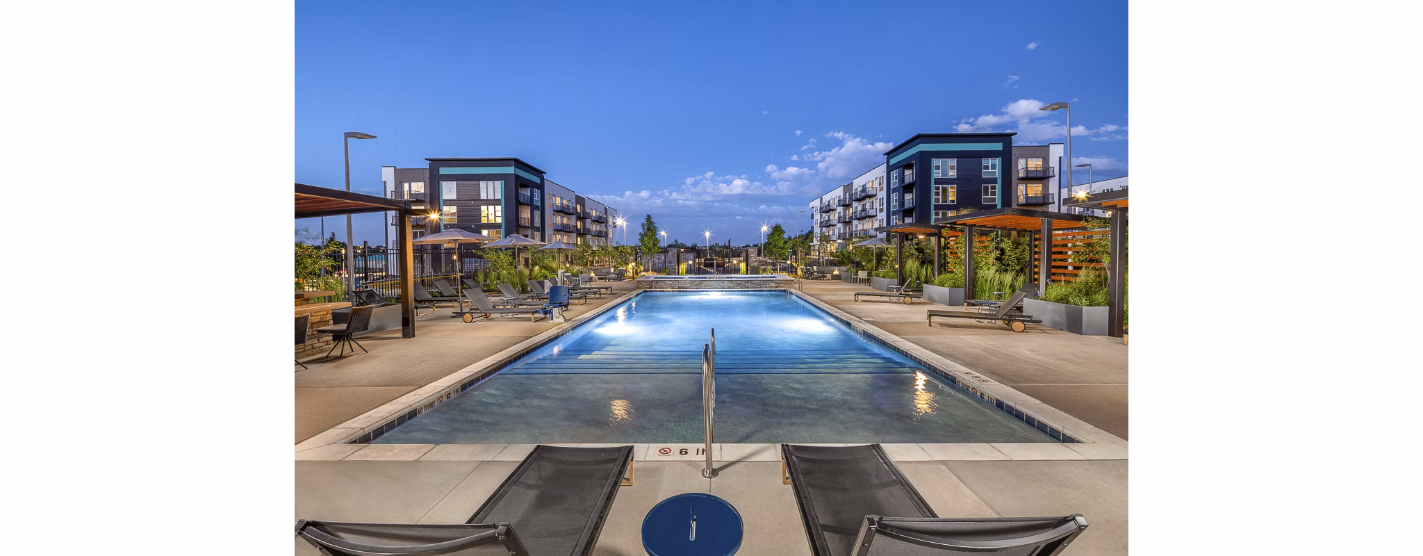 Relaxing pool with lounge chairs at Revel Apartments, ideal for sunny day enjoyment