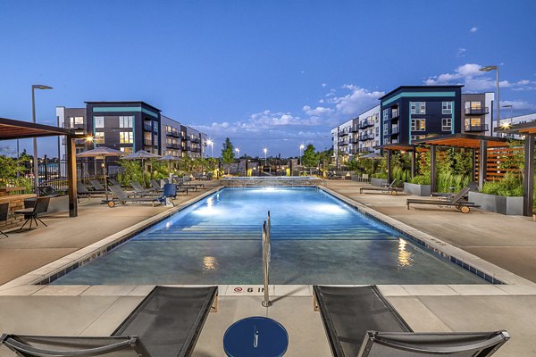 Relaxing pool with lounge chairs at Revel Apartments, ideal for sunny day enjoyment