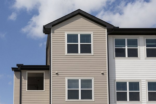 Luxury apartment with beige and white siding and large windows under a blue sky