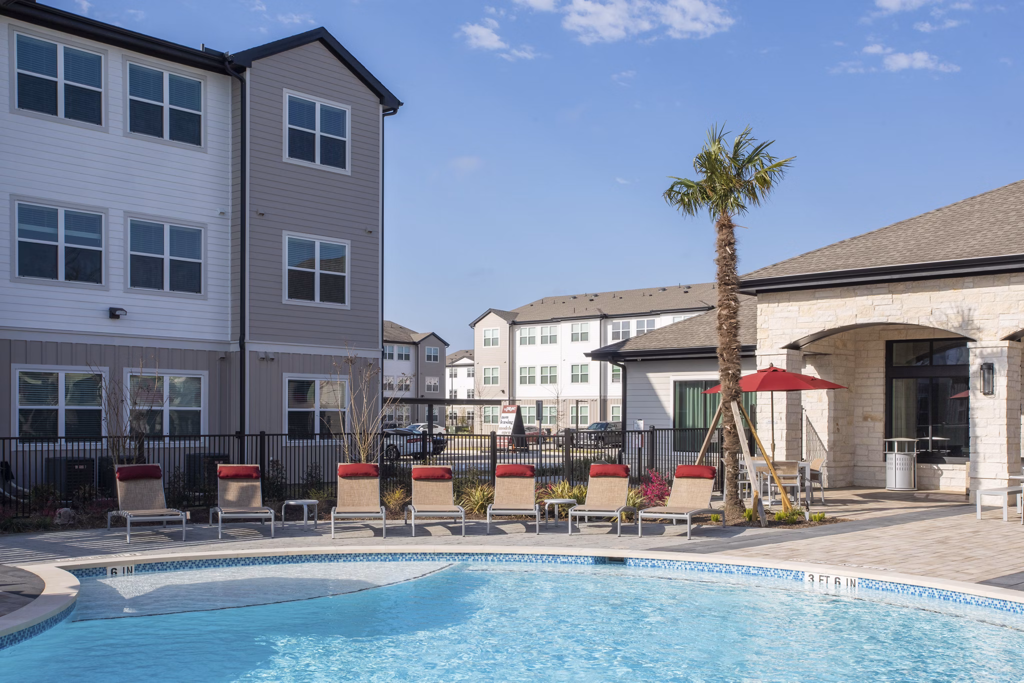 Outdoor swimming pool area with lounge chairs and palm trees in luxury apartments