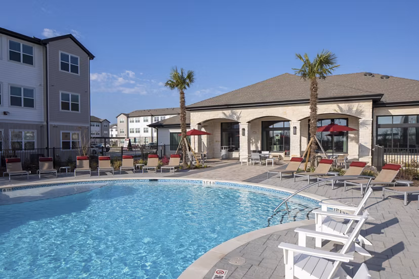 Resort-style swimming pool with lounge chairs and umbrellas in luxury apartments