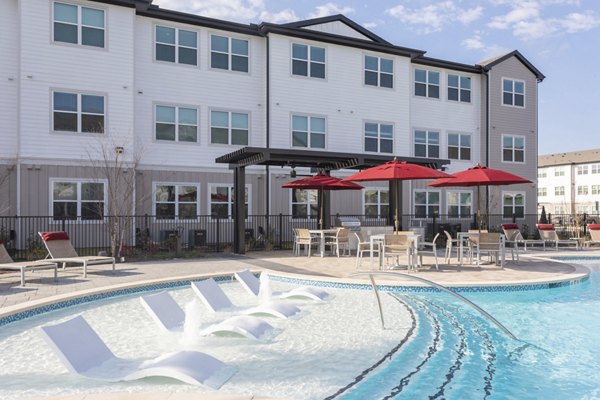 Outdoor swimming pool with lounge chairs and red umbrellas at luxury apartments in a vibrant residential community