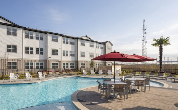 Outdoor swimming pool area with lounge chairs and umbrellas at luxury apartments