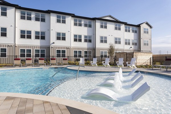 Swimming pool with lounge chairs and a modern residential building in the background at luxury apartments