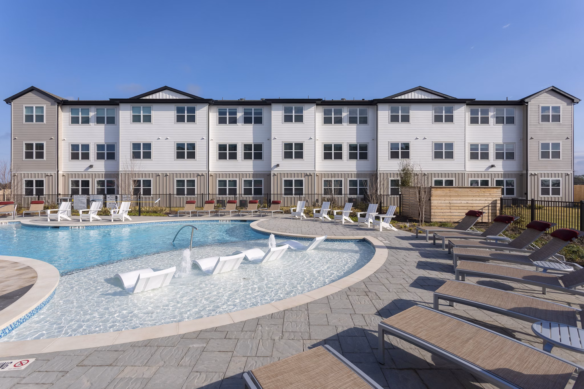 Luxury apartment building with a swimming pool and lounge chairs in the foreground