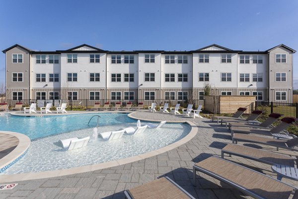 Luxury apartment building with a swimming pool and lounge chairs in the foreground