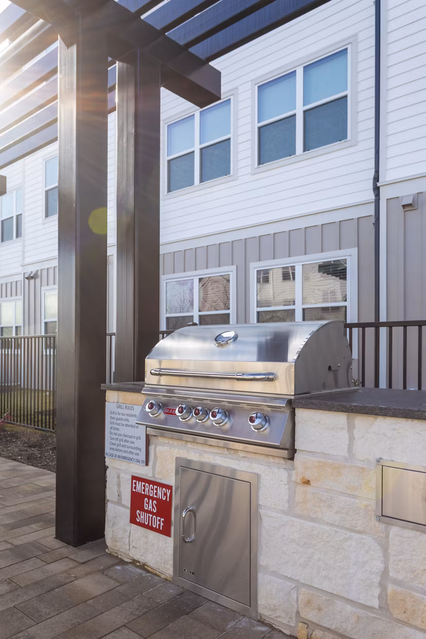 Fenced grassy area with nearby buildings and parked cars at luxury apartments