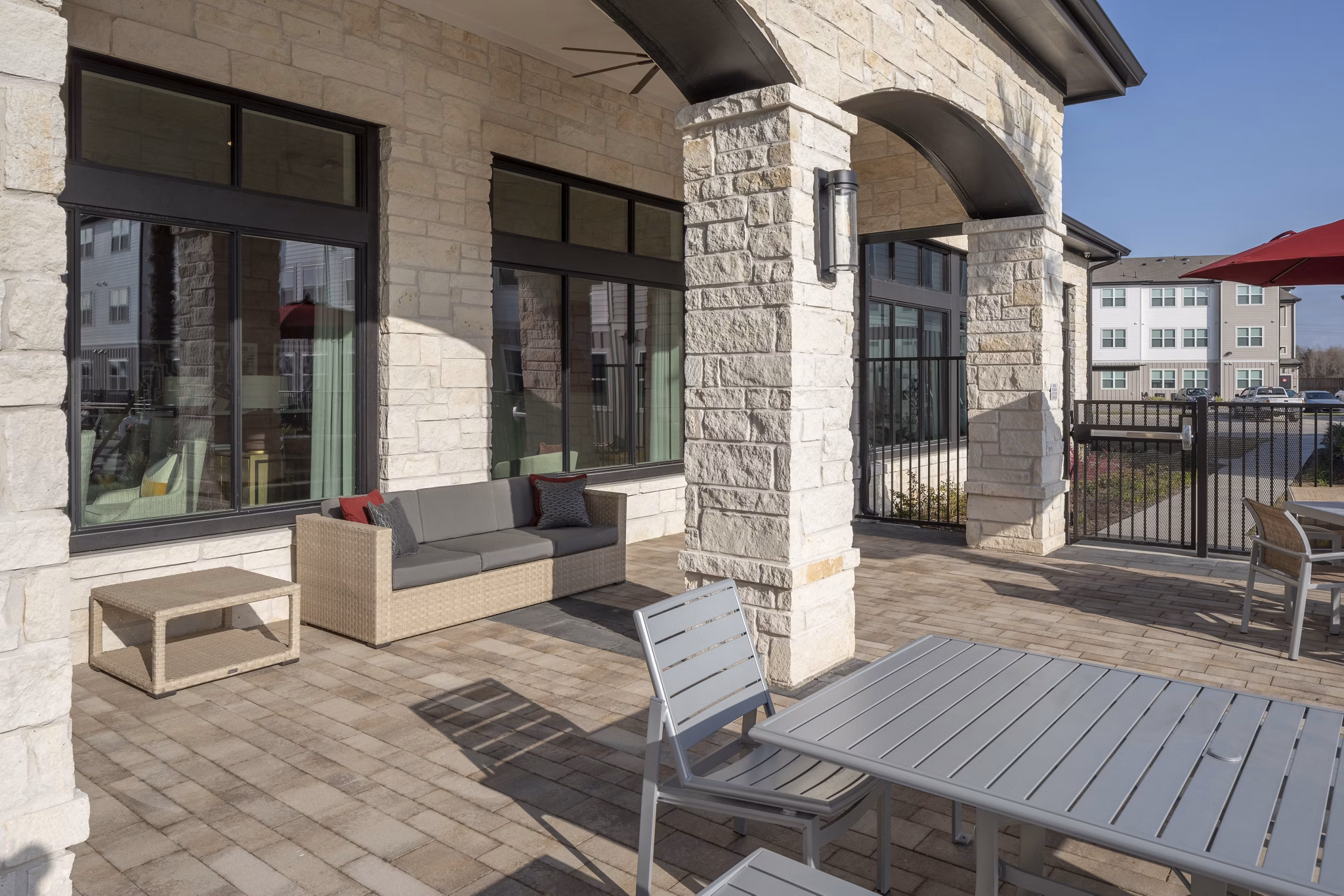 Outdoor patio area with stone pillars, couch, and dining table at luxury apartments