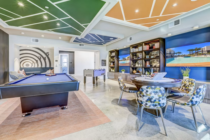 Clubhouse game room featuring pool table and lounge seating at Encore Motif Apartments, ideal for social gatherings and entertainment