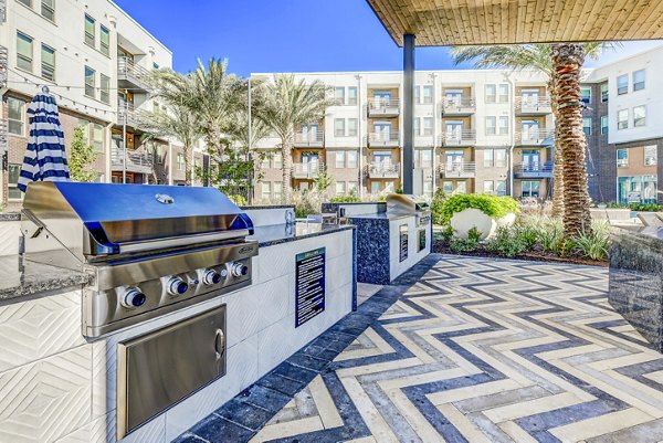 Outdoor grill area with patio seating at Encore Motif Apartments
