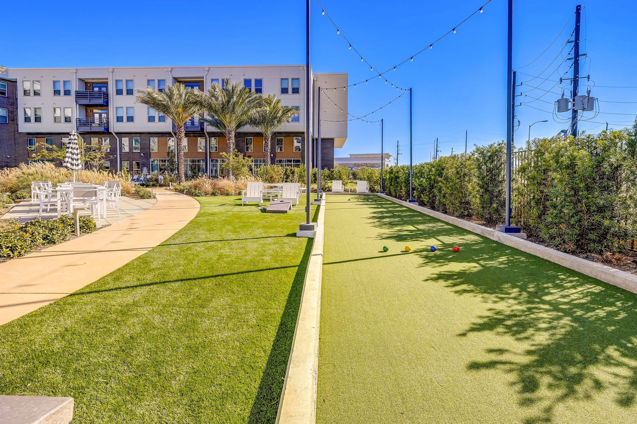 Bocce ball court surrounded by lush greenery at Encore Motif Apartments