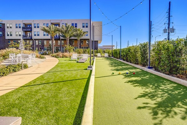 Bocce ball court surrounded by lush greenery at Encore Motif Apartments