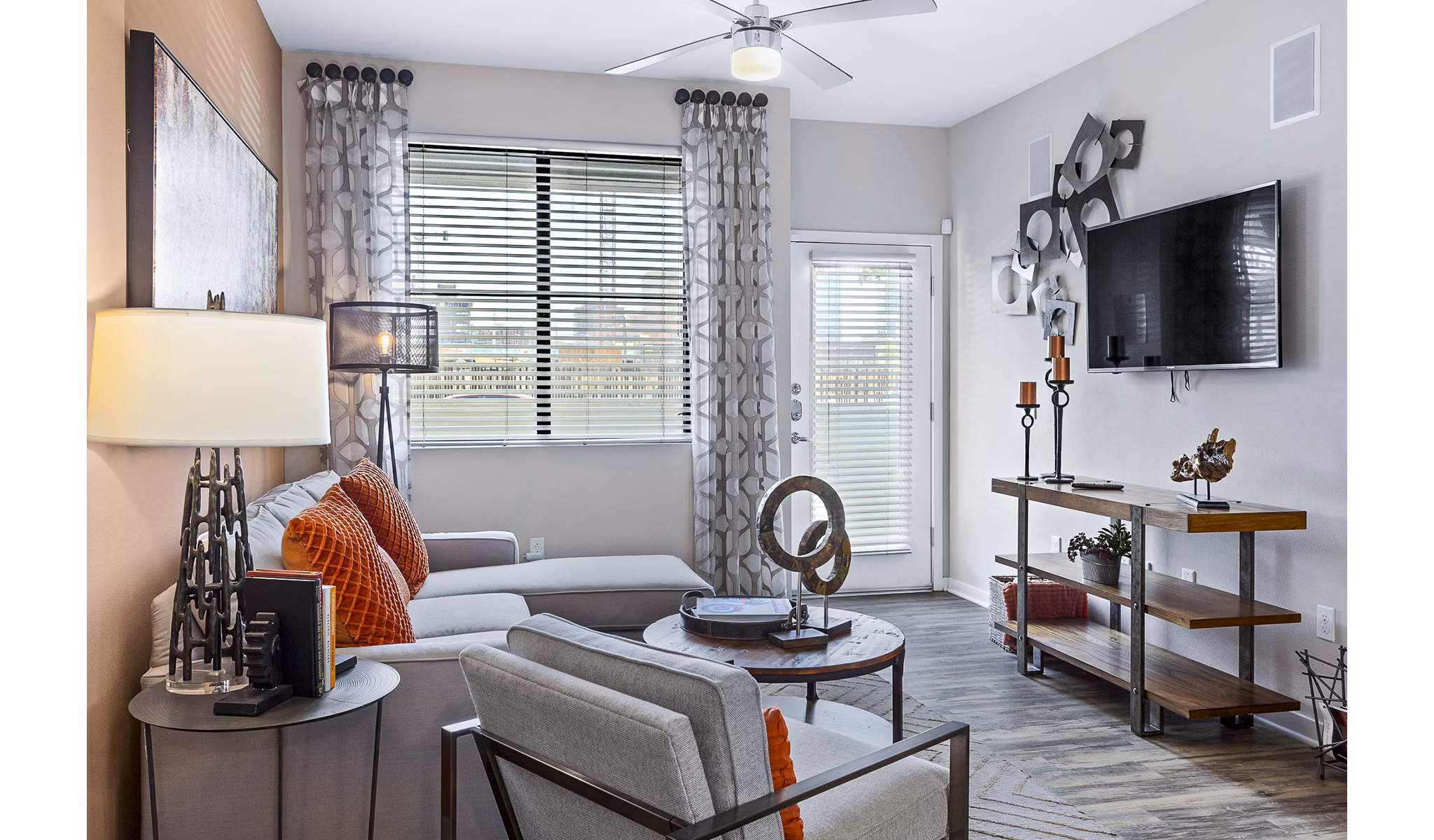 Living room with modern decor, large windows, and hardwood floors in 601 PAX Apartments, offering luxury living in an urban setting