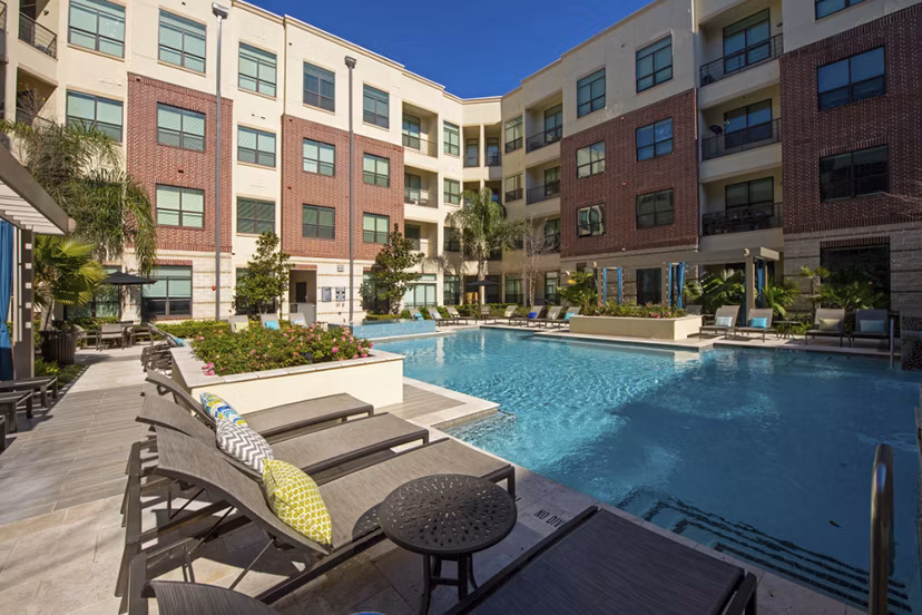 Infinity-edge pool at Millennium High Street Apartments with lounge seating and lush landscaping