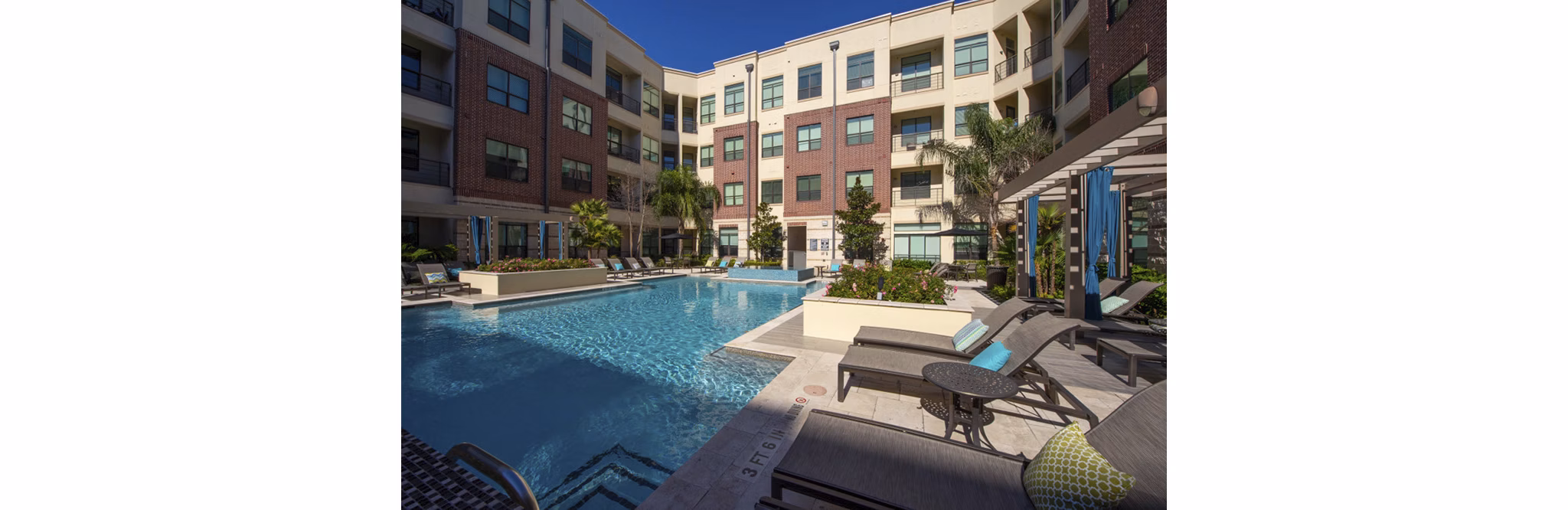 Luxurious outdoor pool area at Millennium High Street Apartments featuring modern seating and lush landscaping