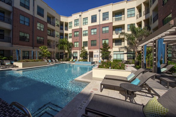 Luxurious outdoor pool area at Millennium High Street Apartments featuring modern seating and lush landscaping