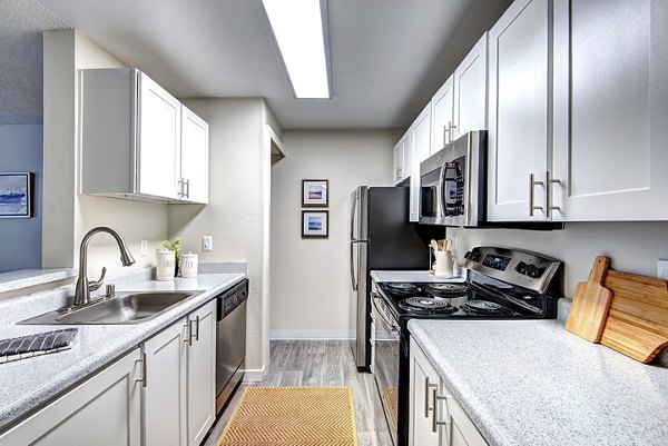 Modern kitchen featuring stainless steel appliances and granite countertops at The Becket Apartments