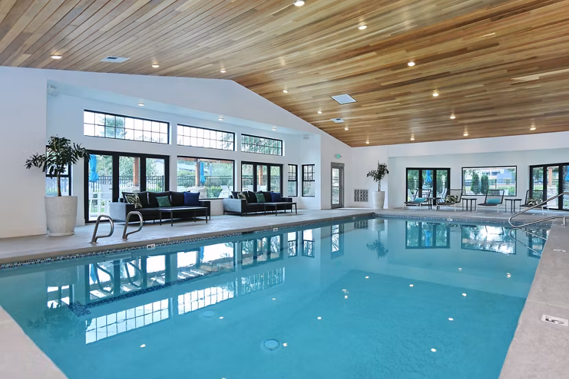 Indoor pool with lounge seating and modern lighting at The Becket Apartments