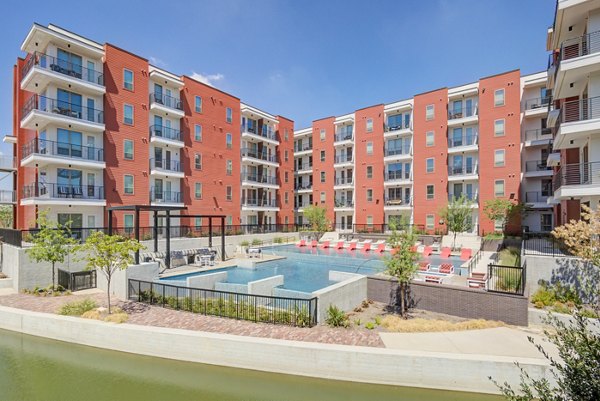 Relaxing pool area at Encore Panther Island Apartments, featuring sun loungers and serene surroundings