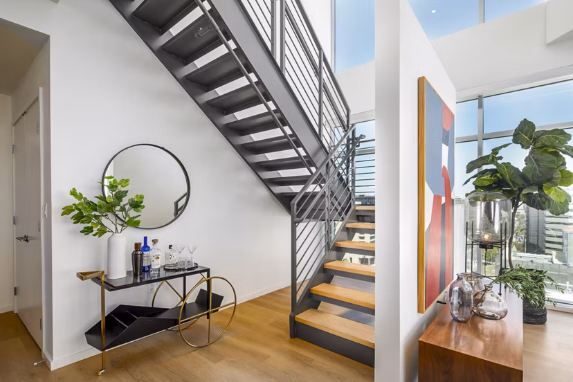 Open living room with elegant stairway at 200 West Ocean Apartments, a luxury community by Greystar