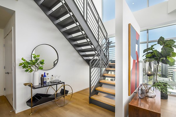 Open living room with elegant stairway at 200 West Ocean Apartments, a luxury community by Greystar