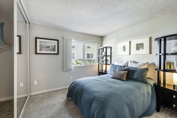 Cozy bedroom with modern decor at The Breakwater Apartments, featuring luxury furnishings and ample natural light