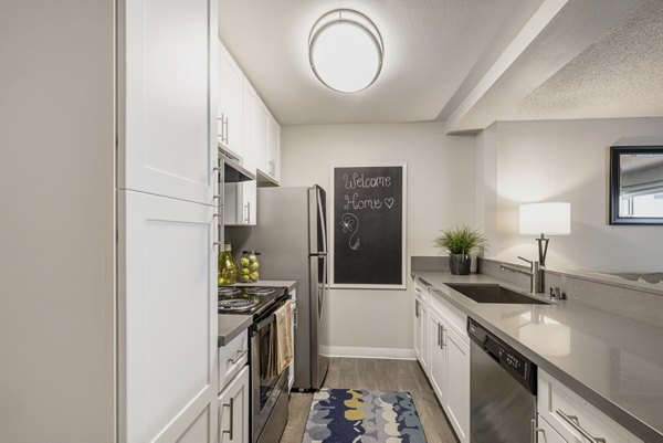 Modern kitchen featuring stainless steel appliances and granite countertops at The Breakwater Apartments