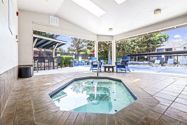 Relaxing hot tub surrounded by lush greenery at Avana Hamptons Apartments