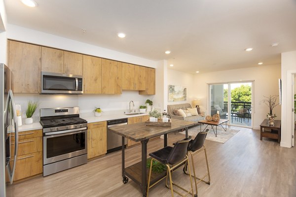 Modern kitchen with stainless steel appliances and marble countertops in One38 Apartments