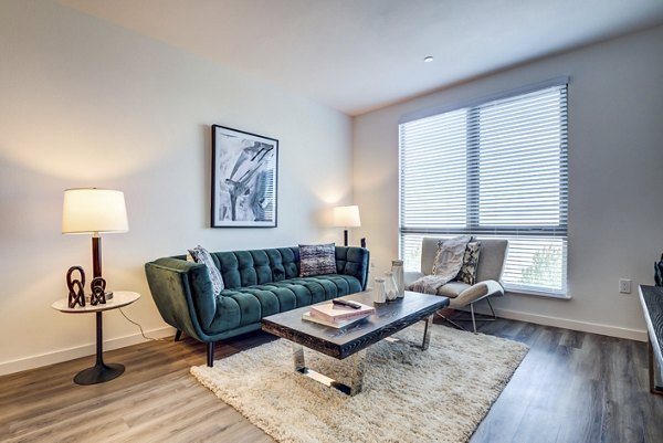 Modern living room with plush seating and bay window at The Exchange at Bayfront Apartments