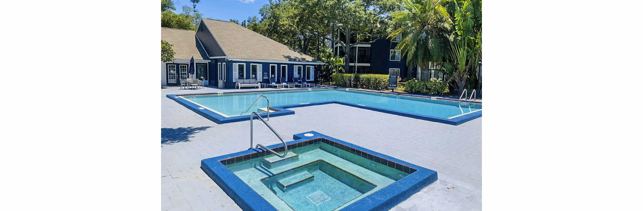 Outdoor swimming pool at Avana Lakeview Apartments with modern lounge chairs and scenic views