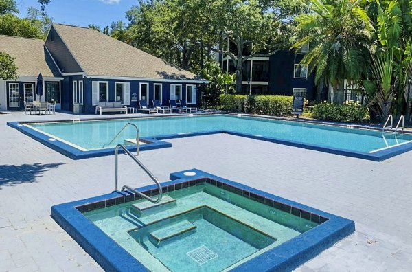 Outdoor swimming pool at Avana Lakeview Apartments with modern lounge chairs and scenic views