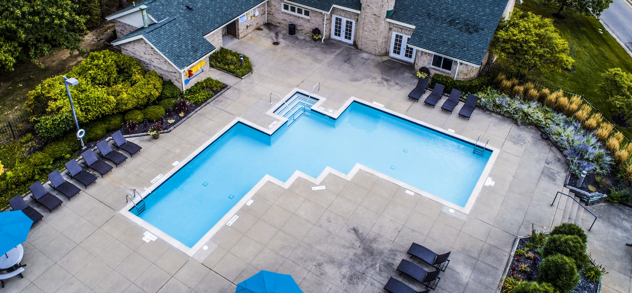 Serene outdoor pool area at Hidden Lakes Apartments, surrounded by lush greenery and comfortable lounges for relaxation