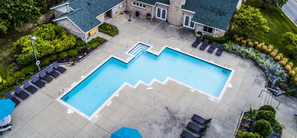 Serene outdoor pool area at Hidden Lakes Apartments, surrounded by lush greenery and comfortable lounges for relaxation