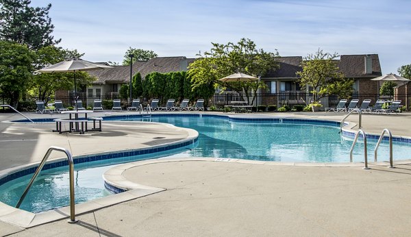 Poolside relaxation area with deck chairs and umbrellas at Oak Hill Apartments
