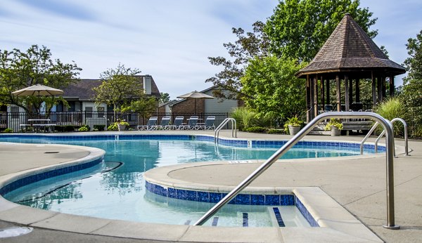 Infinity pool with loungers and landscaped surroundings at Oak Hill Apartments