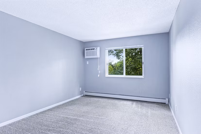 Cozy bedroom with large windows at Avana West Park Apartments