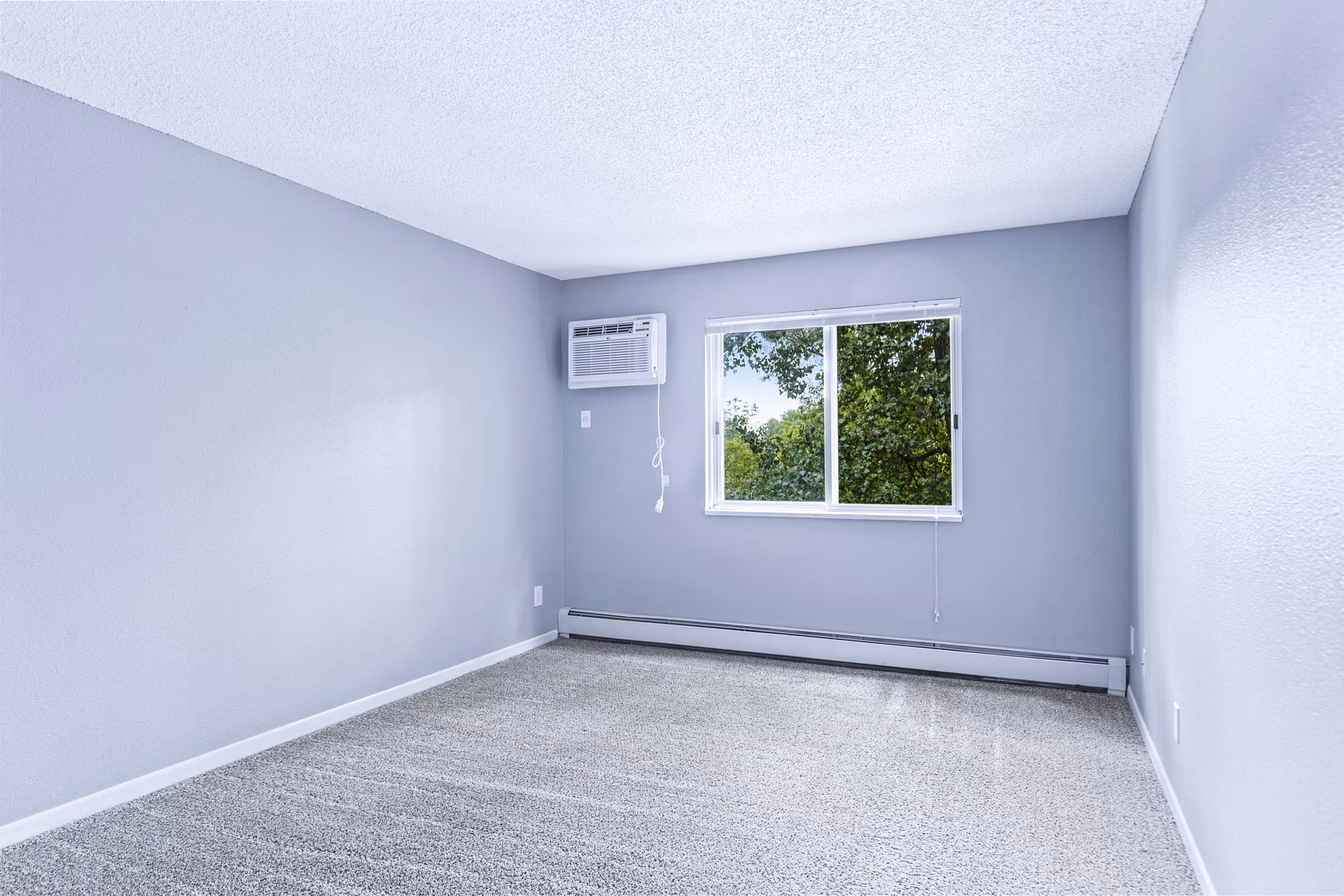 Cozy bedroom with large windows at Avana West Park Apartments