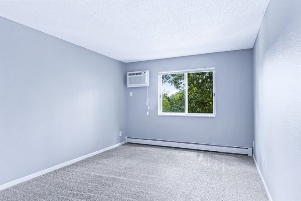 Cozy bedroom with large windows at Avana West Park Apartments