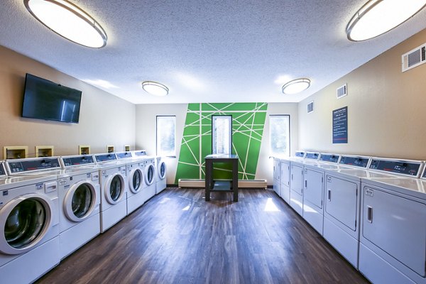 Laundry room with modern machines and ample folding space at Avana West Park Apartments, offering convenient on-site laundry services
