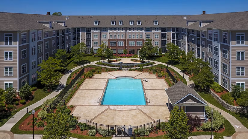 Outdoor swimming pool with lounge chairs and modern apartment building in the background